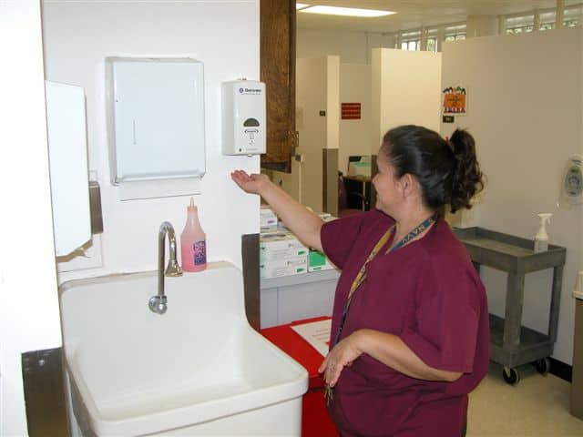 A Woman using touchless hand sanitiser dispenser to get the sanitiser