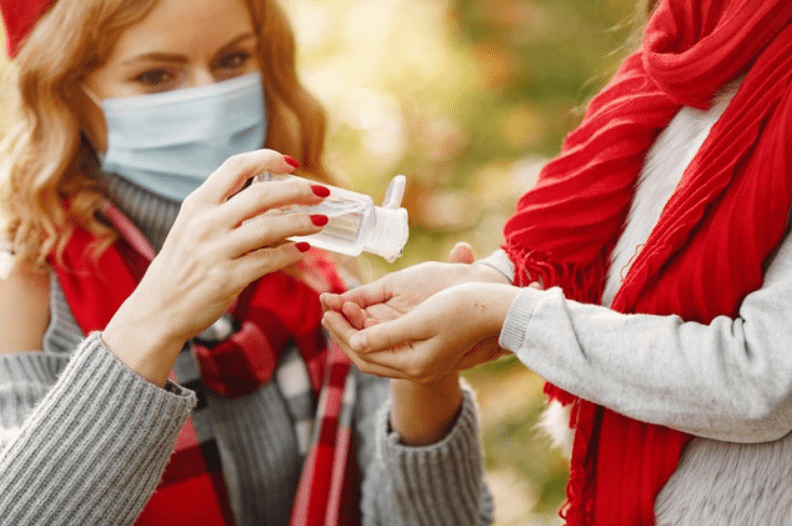 A woman help a child to use hand sanitiser